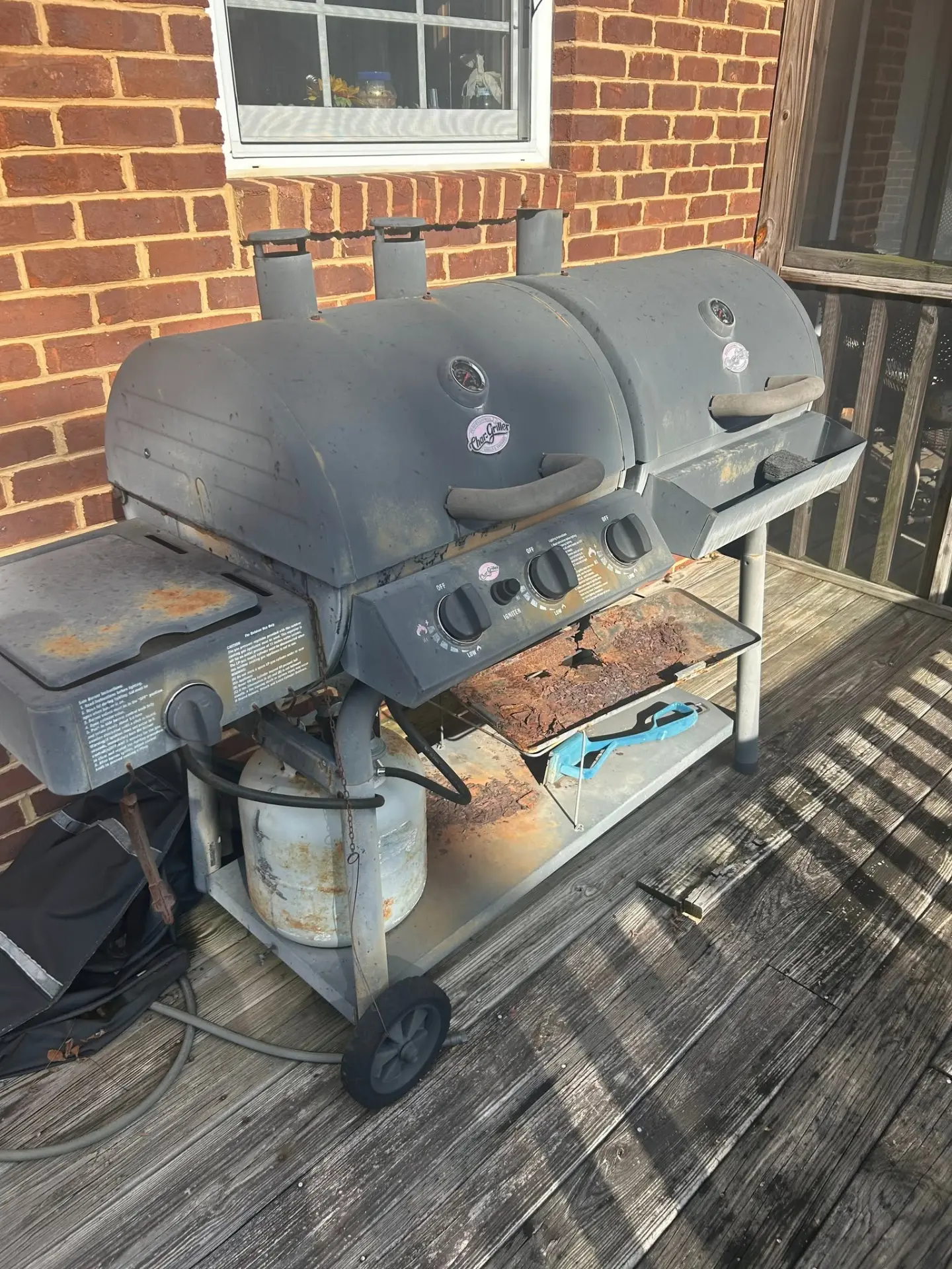 Rusted old gas grill on a wooden deck ready for appliance disposal