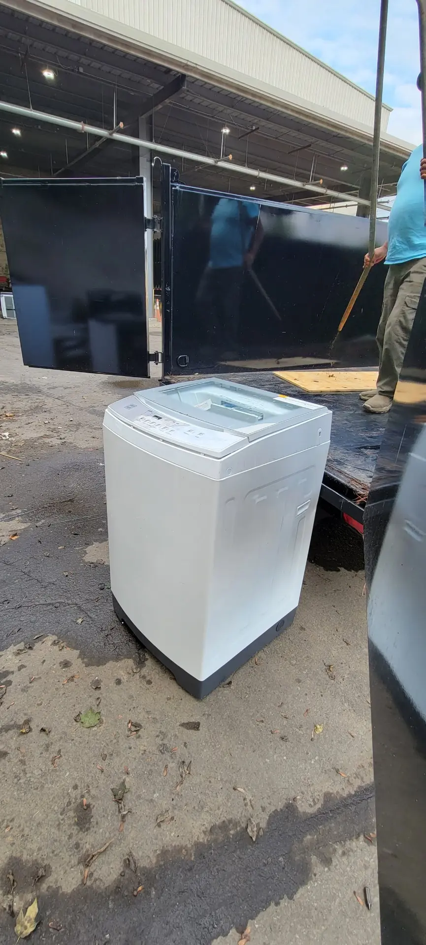 Washing machine being loaded into a junk removal trailer