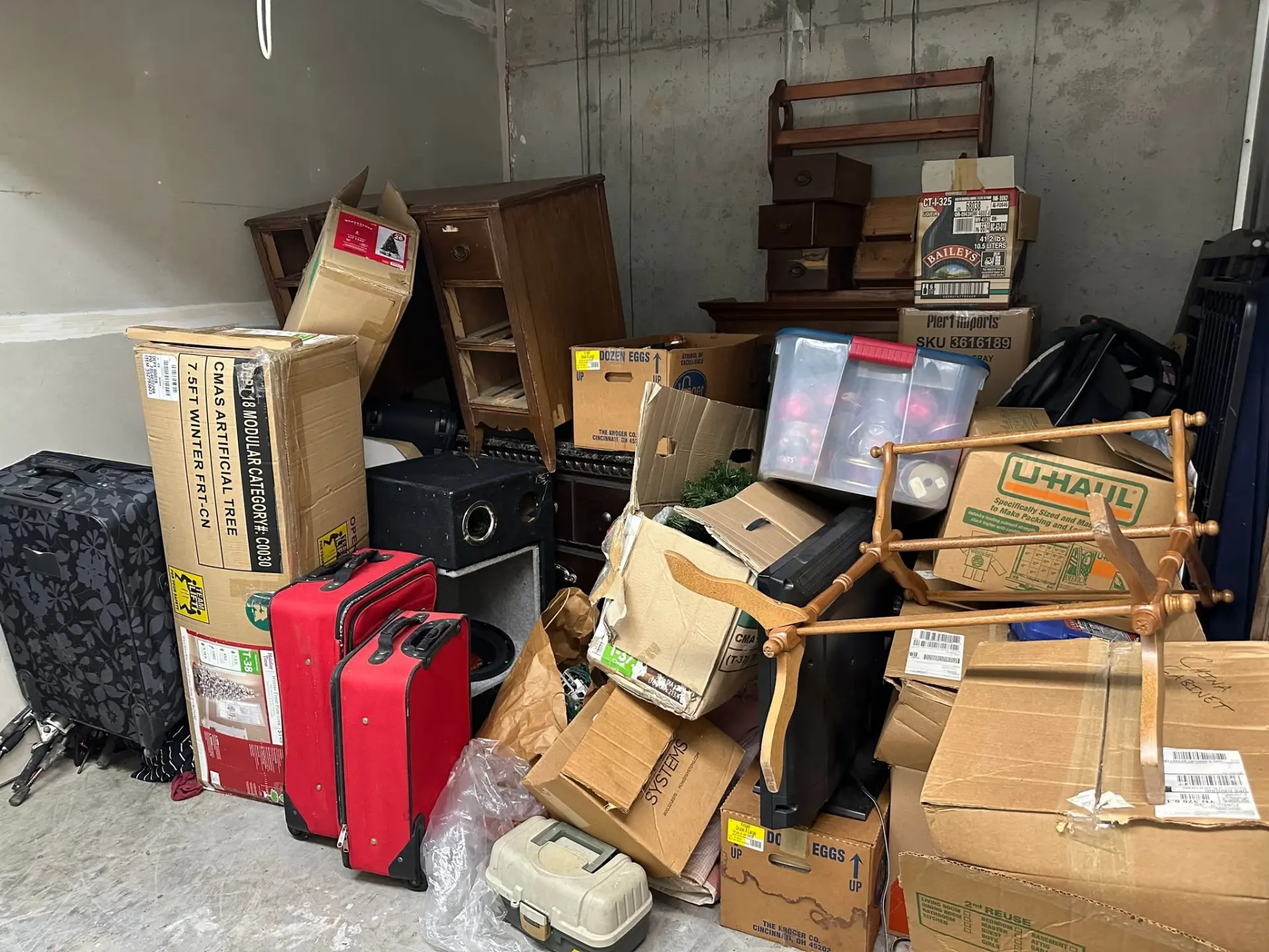 Garage cleanout with stacked boxes, suitcases, furniture and household junk
