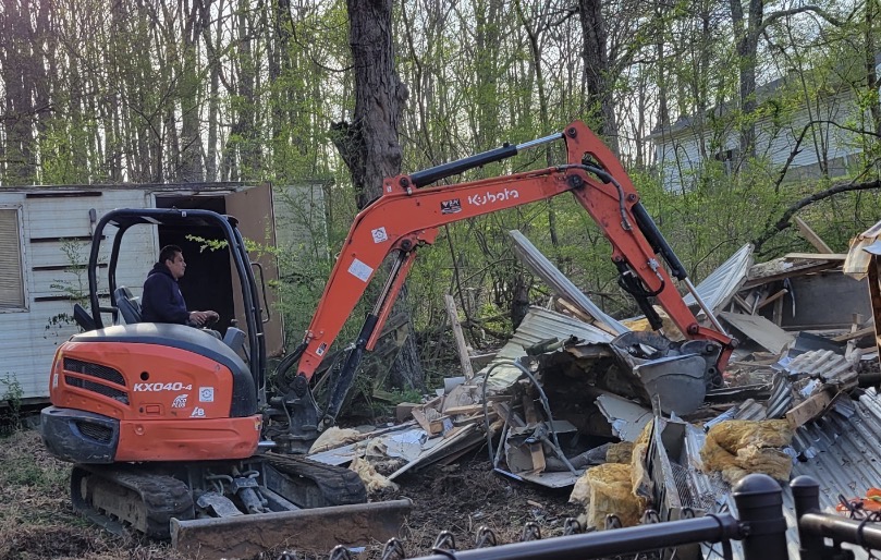 Excavator loading debris from a Knoxville cleanup project