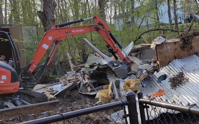 Excavator clearing demolition debris during a property cleanout